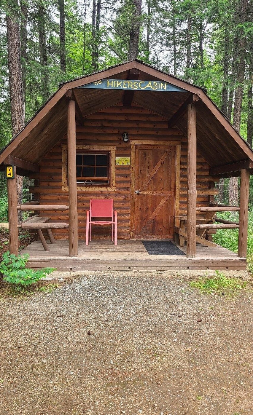 A small log glamping cabin with a porch