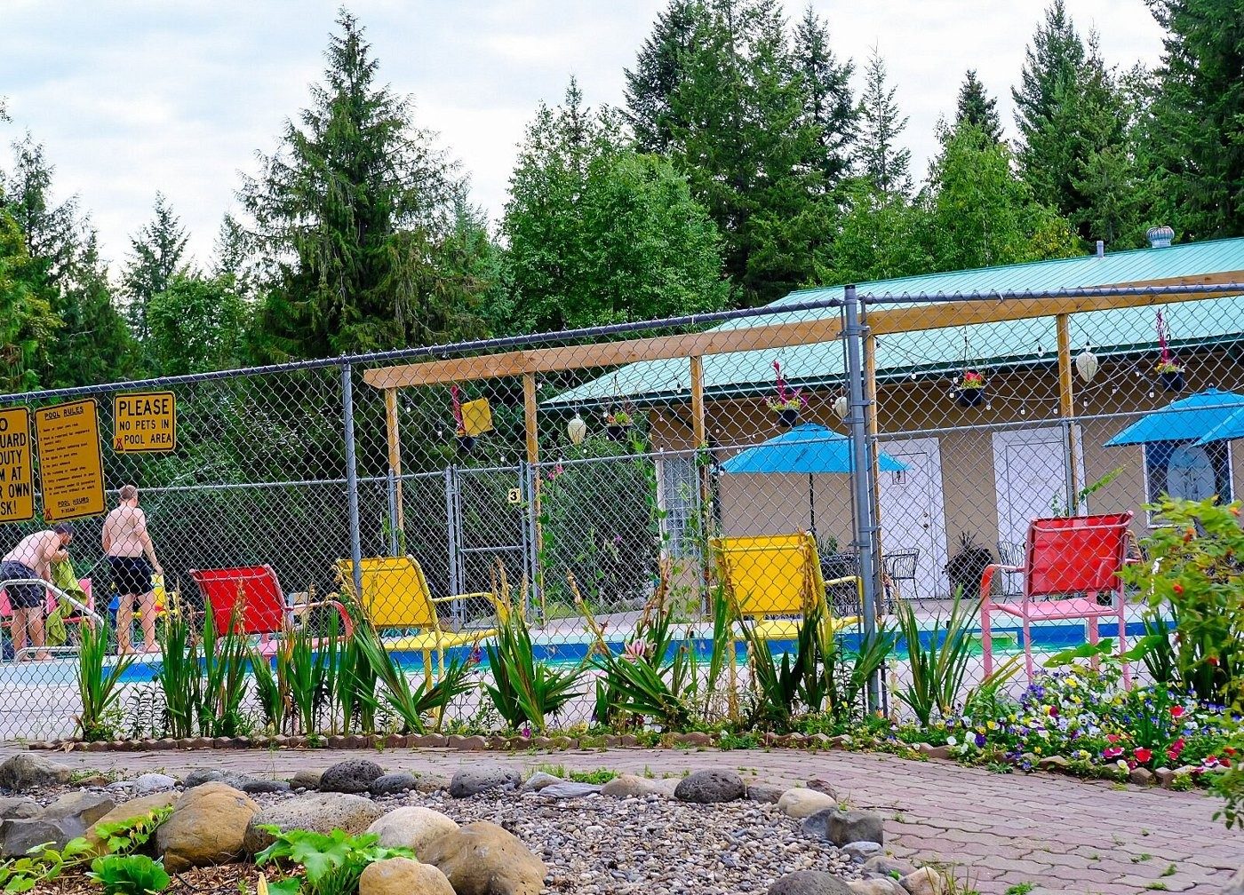 An outdoor heated pool with red and yellow lounge chairs