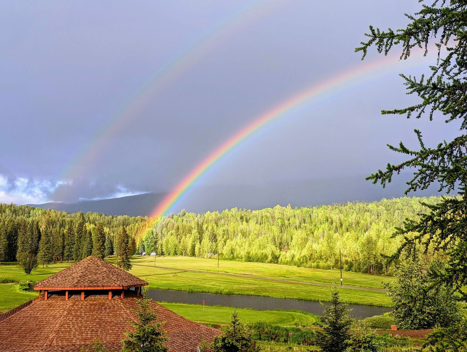 A double rainbow over the valley seen from beside a large timber gazebo